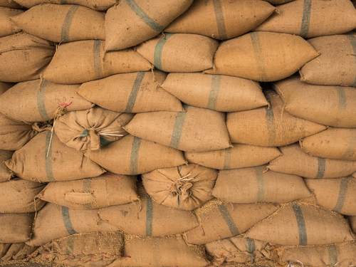 Old hemp sacks containing rice placed stacked in a row
