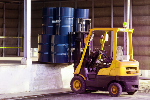 forklift carrying load of shipping drums to loading dock