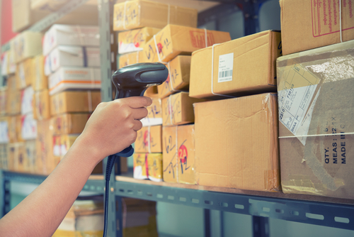 worker scanning package barcode on racking system