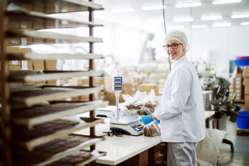 woman measuring cookies on scale for packaging