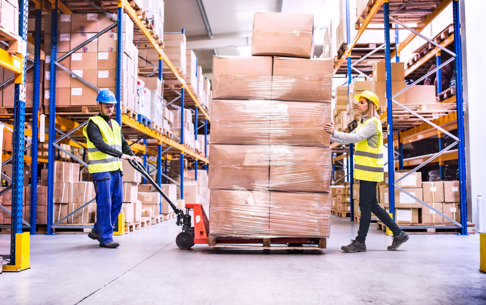 a pair of warehouse workers pulling a pallet jack