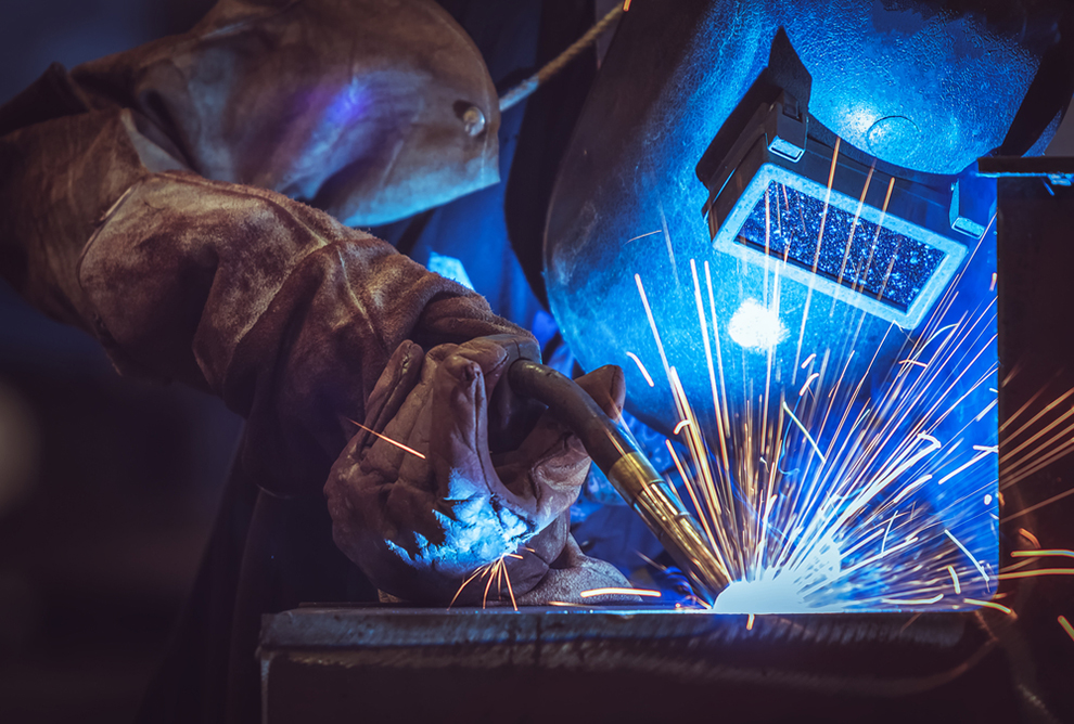 a worker welding with a welding mask on