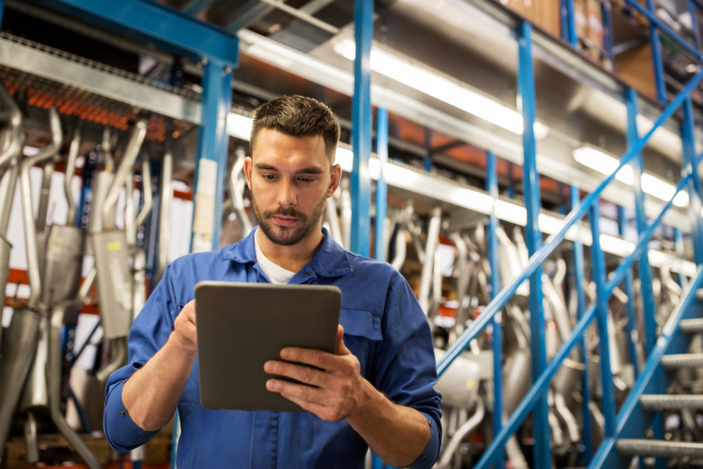 a worker using a tablet in an automotive warehouse