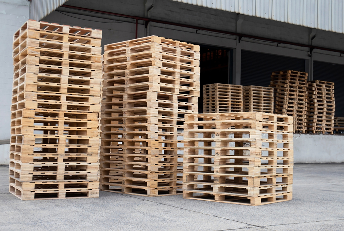 several stacks of plain wood pallets outside a loading bay
