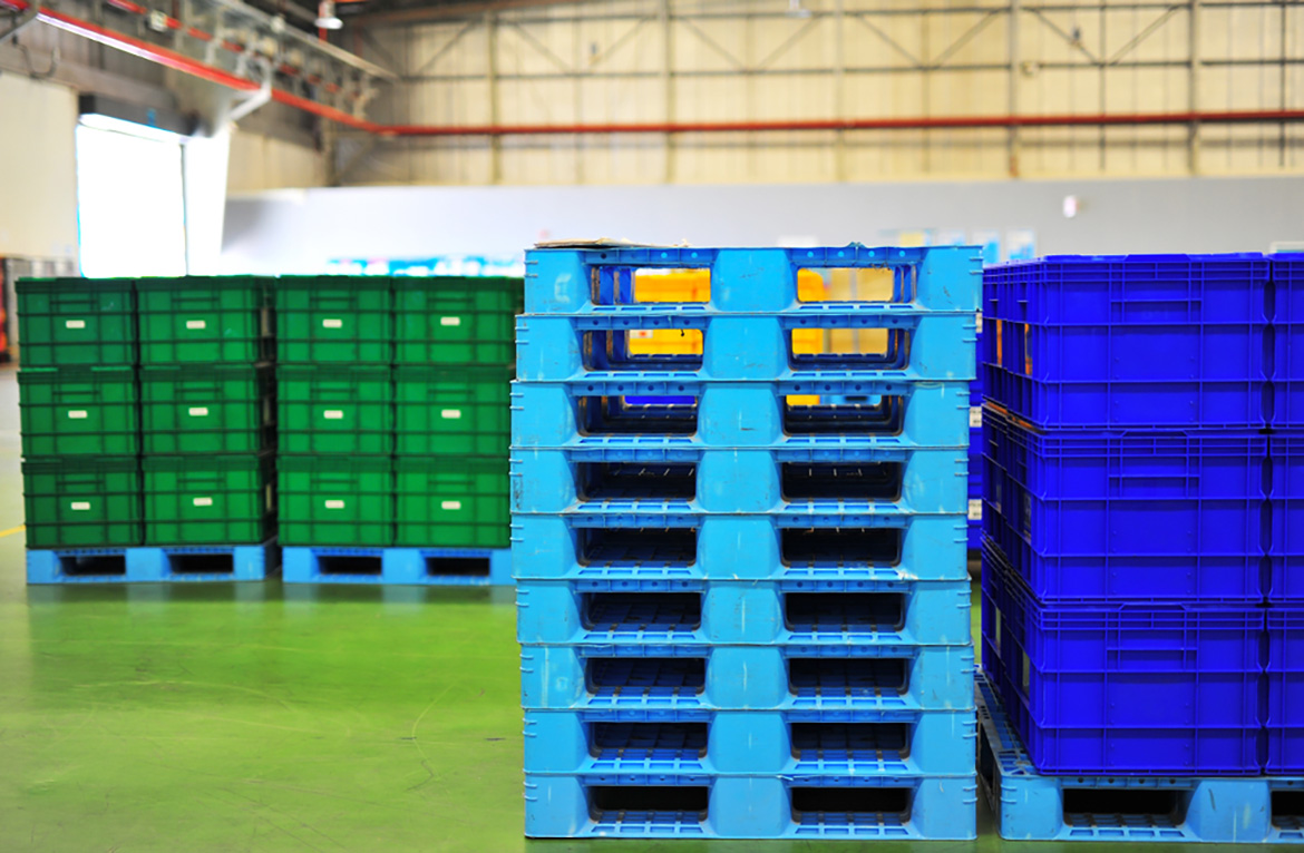 stacks of containers on blue pallets next to a stack of blue pallets